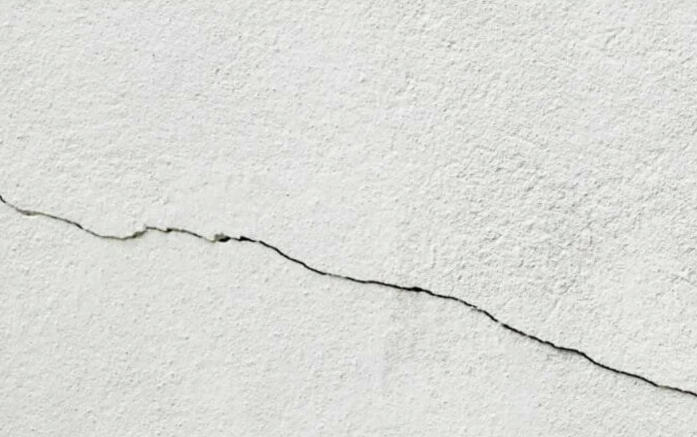 Settlement crack running across a textured ceiling, taped rather than filled