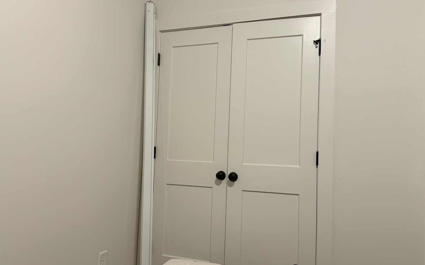 Double closet doors hung with matching trim and black hardware