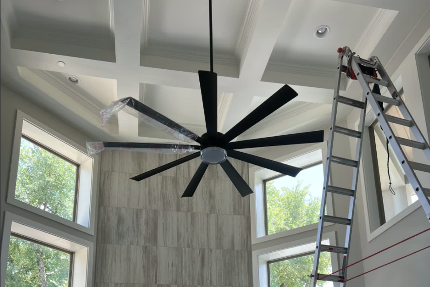 Large eight-blade fan going up on a coffered ceiling, blades still wrapped