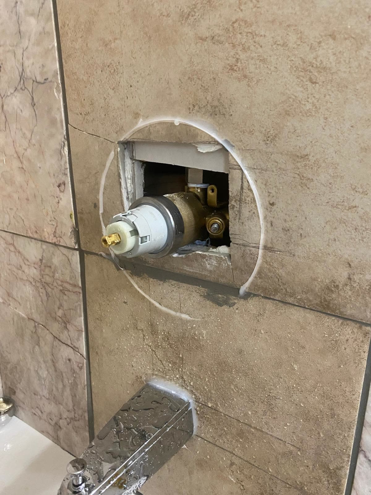 Shower valve cartridge and brass body reached through a cut in the tile